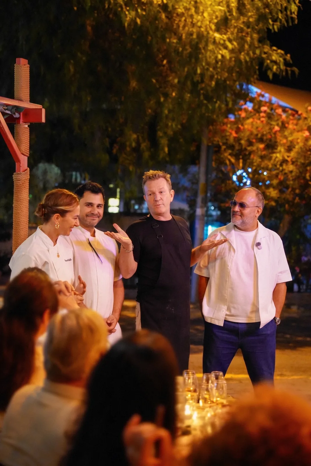 Açık havada bir akşam yemeğinde şefler misafirlerle sohbet ediyor